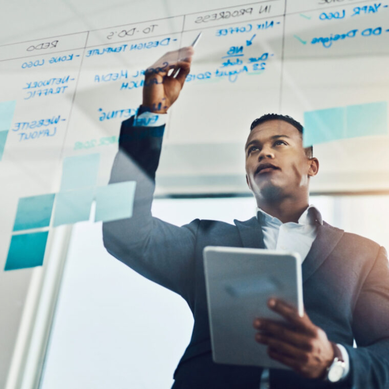 Business leader in a UK office using digital tools and a strategic board to visualise performance, representing how finance teams unlock NetSuite ERP benefits for smarter decision-making and growth.