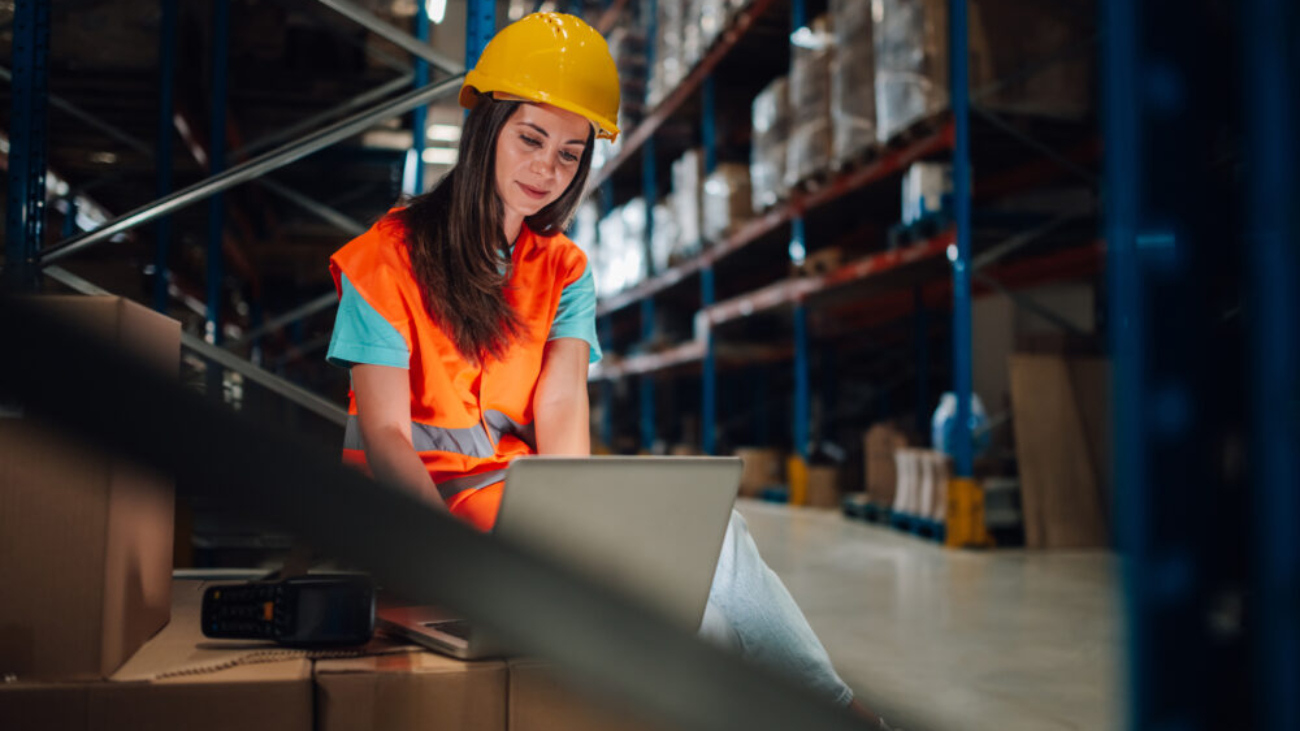 Warehouse employee using a laptop to monitor stock levels – showcasing NetSuite ERP benefits for smarter inventory management in a modern distribution centre.
