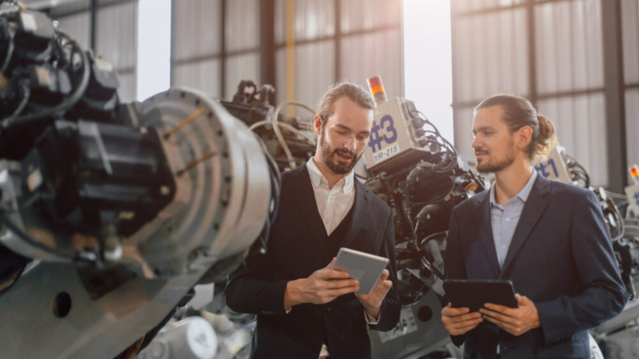Businessman working in robotic factory supported by Manufacturing Software Systems