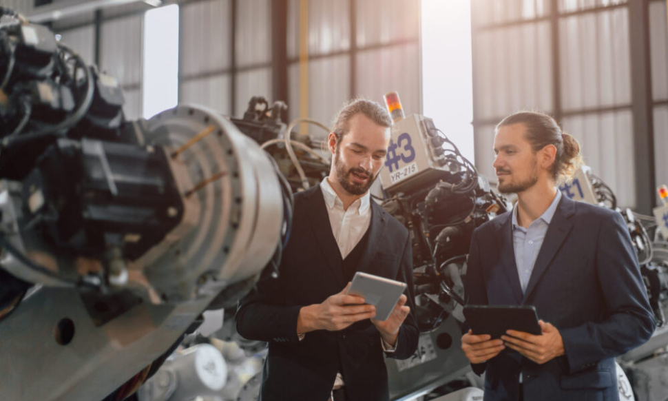 Businessman working in robotic factory supported by Manufacturing Software Systems