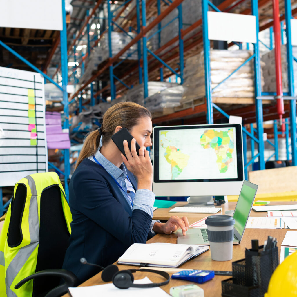 Businesswoman in warehouse on phone using NetSuite warehouse management system software for real-time stock and order management