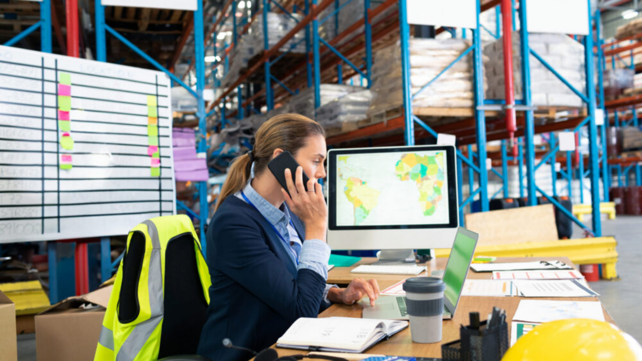 Businesswoman in warehouse on phone using NetSuite warehouse management system software for real-time stock and order management