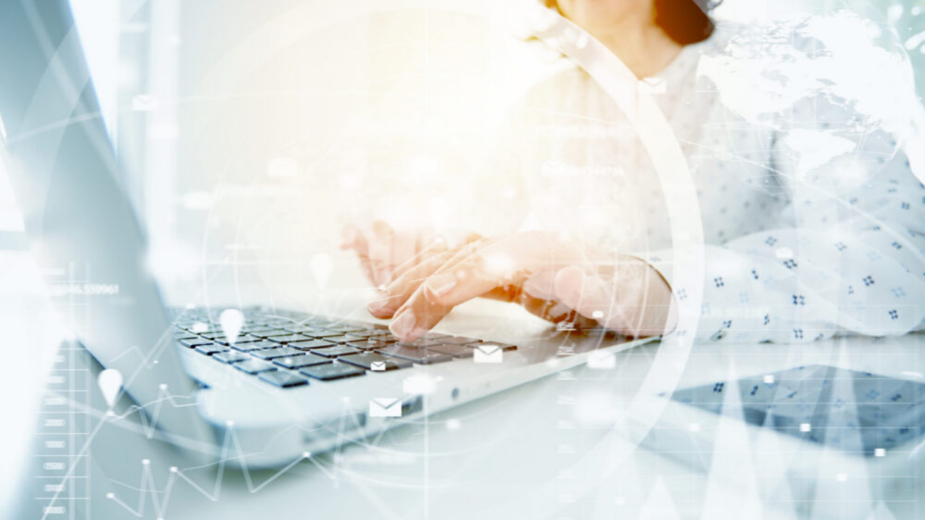 Woman typing on laptop with data overlay representing AI powered accounting software and accounting software with AI insights.