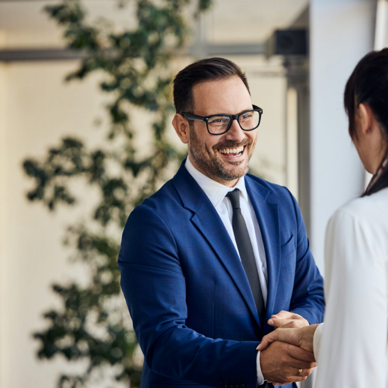 Business partners shaking hands in a modern office after discussing a successful NetSuite implementation project.