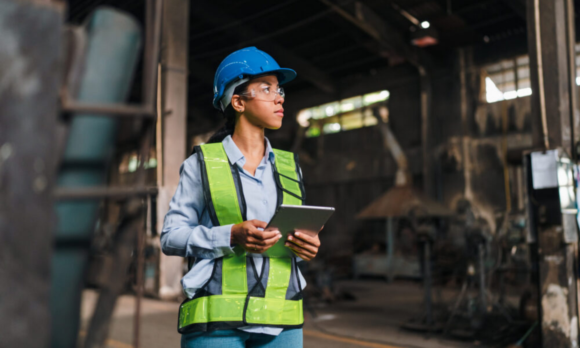 Production manager reviewing manufacturing data on a tablet on the factory floor, representing NetSuite ERP
